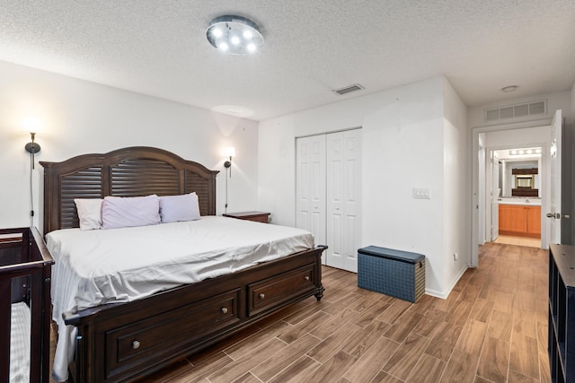 bedroom featuring a closet, connected bathroom, and a textured ceiling