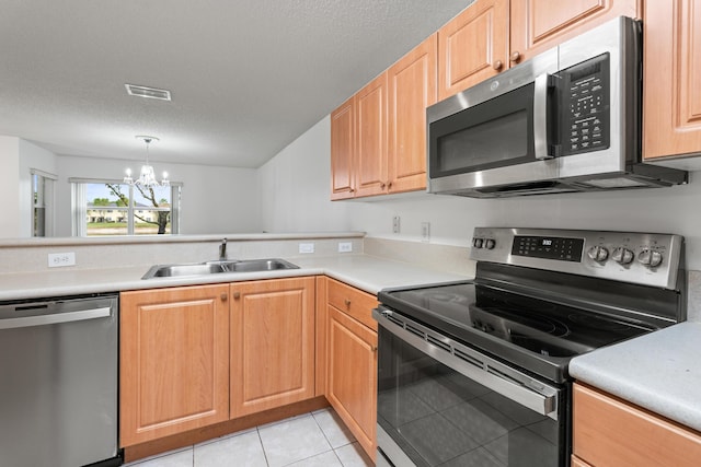 kitchen with pendant lighting, appliances with stainless steel finishes, an inviting chandelier, sink, and light tile patterned floors