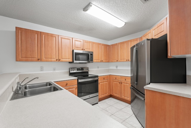 kitchen with light tile patterned floors, sink, stainless steel appliances, and a textured ceiling