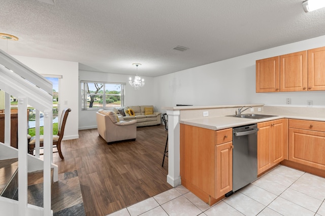 kitchen with pendant lighting, a textured ceiling, sink, kitchen peninsula, and stainless steel dishwasher