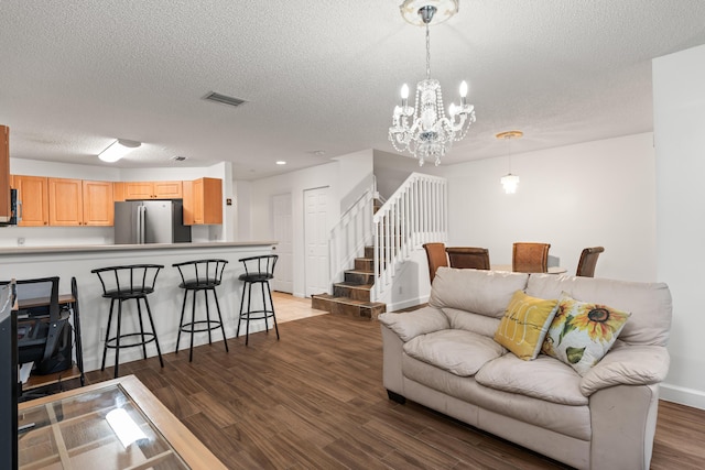 living room featuring a chandelier, wood-type flooring, and a textured ceiling