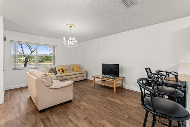 living room featuring a textured ceiling, an inviting chandelier, and dark hardwood / wood-style flooring