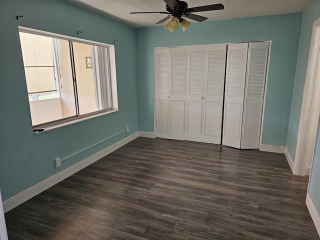 unfurnished bedroom with a textured ceiling, ceiling fan, dark wood-type flooring, and a closet