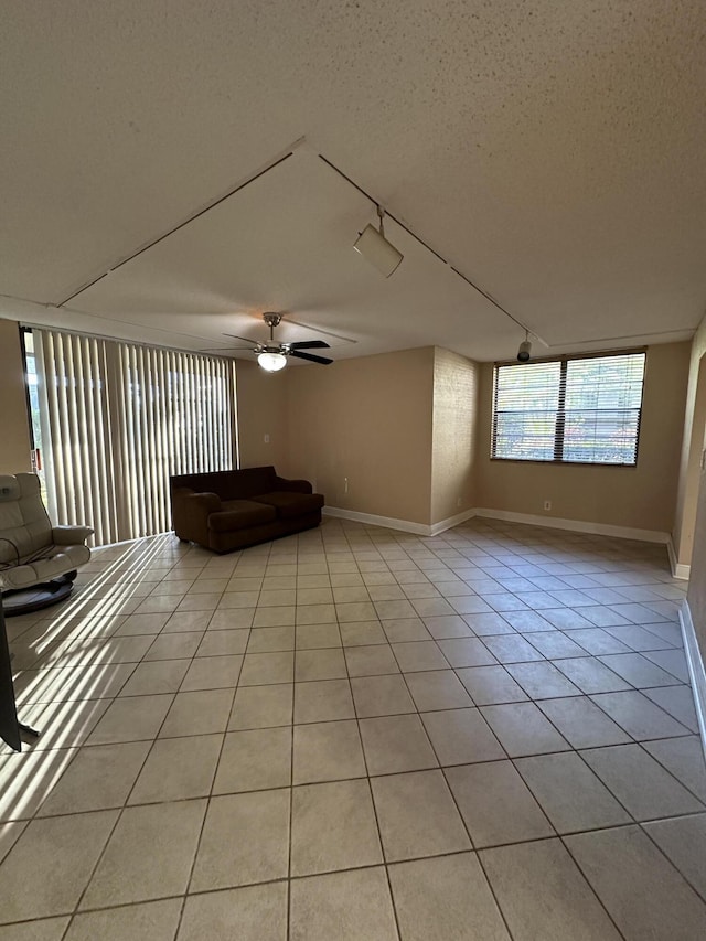 interior space with ceiling fan, light tile patterned floors, track lighting, and a textured ceiling