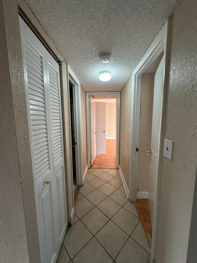 hallway with light tile patterned floors and a textured ceiling