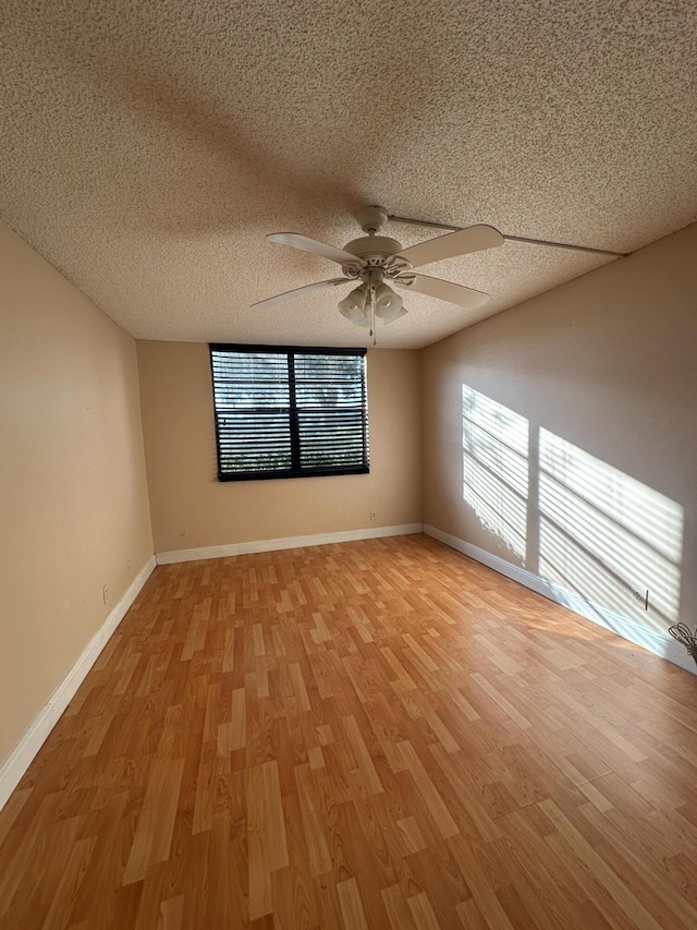 unfurnished room with ceiling fan, a textured ceiling, and light wood-type flooring