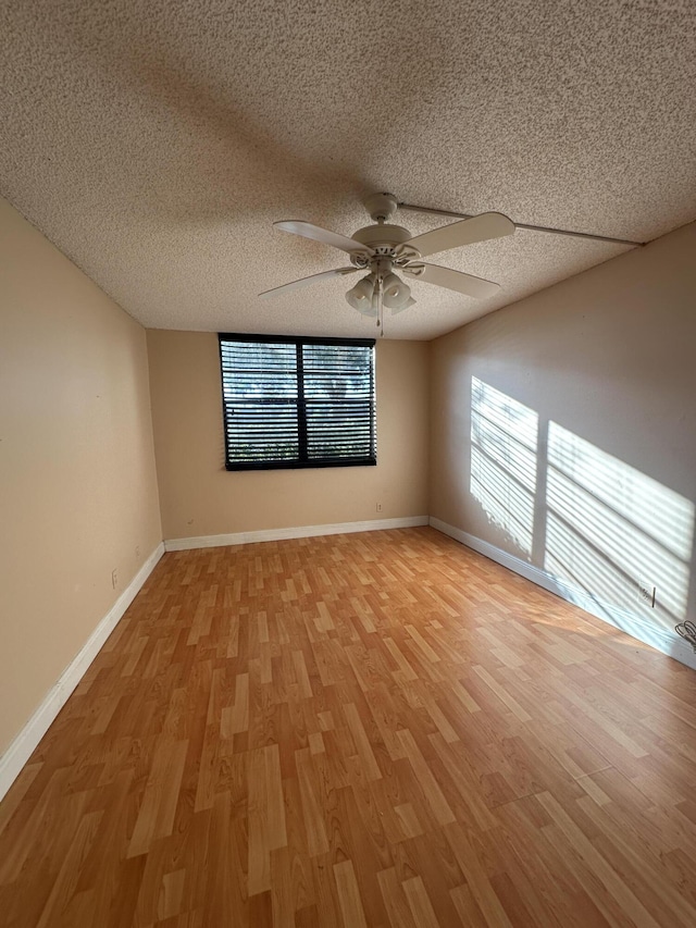 spare room featuring light wood-type flooring, a textured ceiling, and ceiling fan