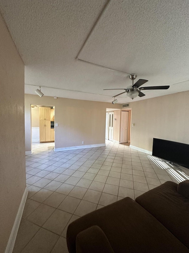 tiled spare room with ceiling fan, track lighting, and a textured ceiling