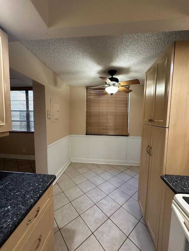 unfurnished dining area with ceiling fan, light tile patterned flooring, and a textured ceiling