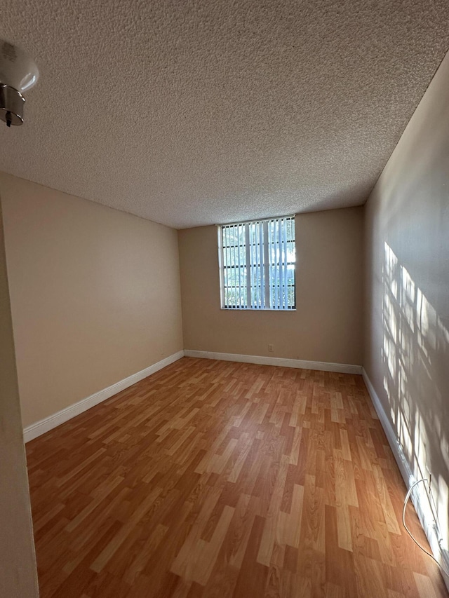 unfurnished room with a textured ceiling and light wood-type flooring