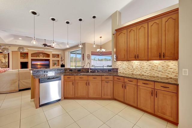 kitchen featuring decorative light fixtures, dark stone countertops, stainless steel dishwasher, sink, and ceiling fan with notable chandelier