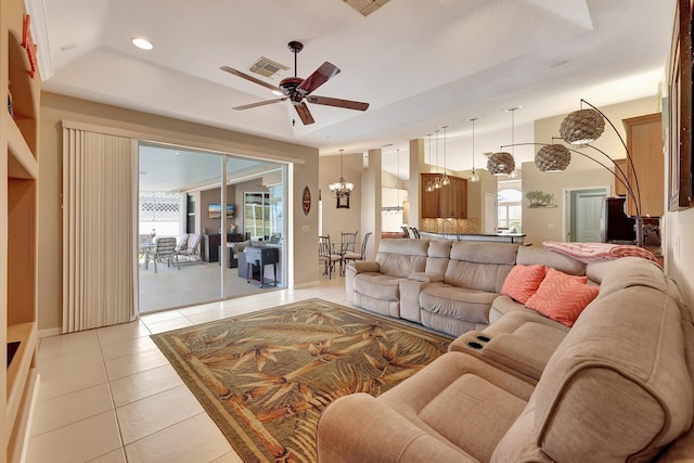 living room featuring ceiling fan with notable chandelier, light tile patterned floors, and a raised ceiling