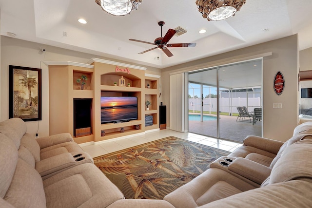 living room with a raised ceiling, ceiling fan, built in features, and light tile patterned flooring