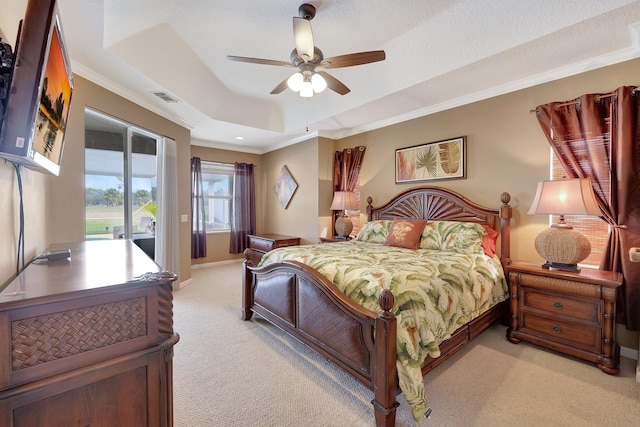 bedroom with ceiling fan, access to outside, a tray ceiling, light colored carpet, and crown molding