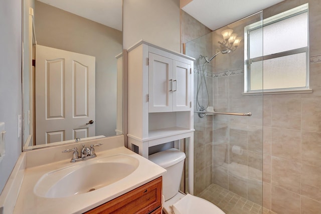 bathroom with toilet, vanity, and tiled shower