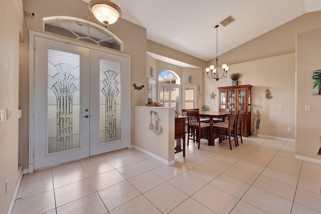 entrance foyer featuring french doors, vaulted ceiling, light tile patterned flooring, and a chandelier