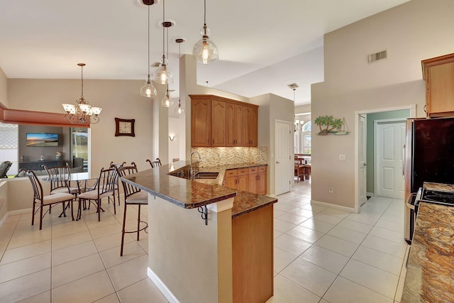 kitchen with a breakfast bar, pendant lighting, stainless steel fridge, and kitchen peninsula