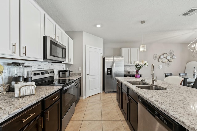 kitchen featuring stainless steel appliances, sink, pendant lighting, an inviting chandelier, and white cabinetry