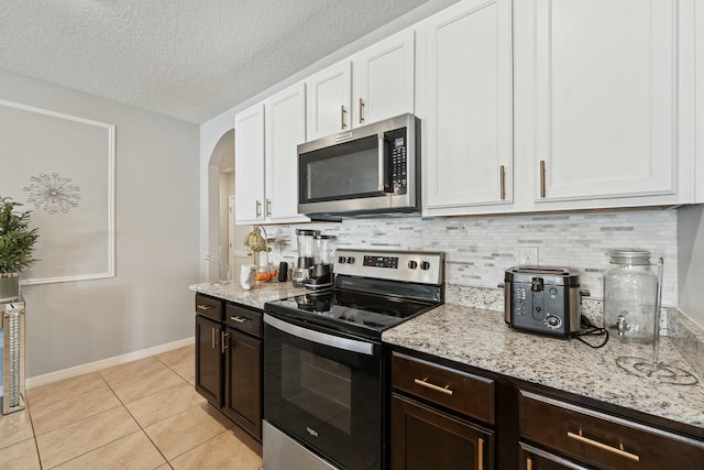 kitchen with white cabinets, light stone countertops, light tile patterned floors, and stainless steel appliances