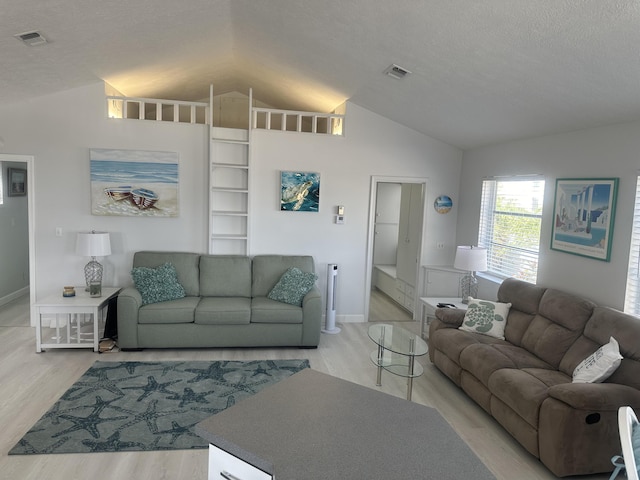 living room featuring a textured ceiling, vaulted ceiling, and light wood-type flooring