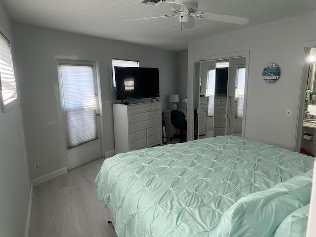 bedroom with a textured ceiling, light hardwood / wood-style floors, and ceiling fan