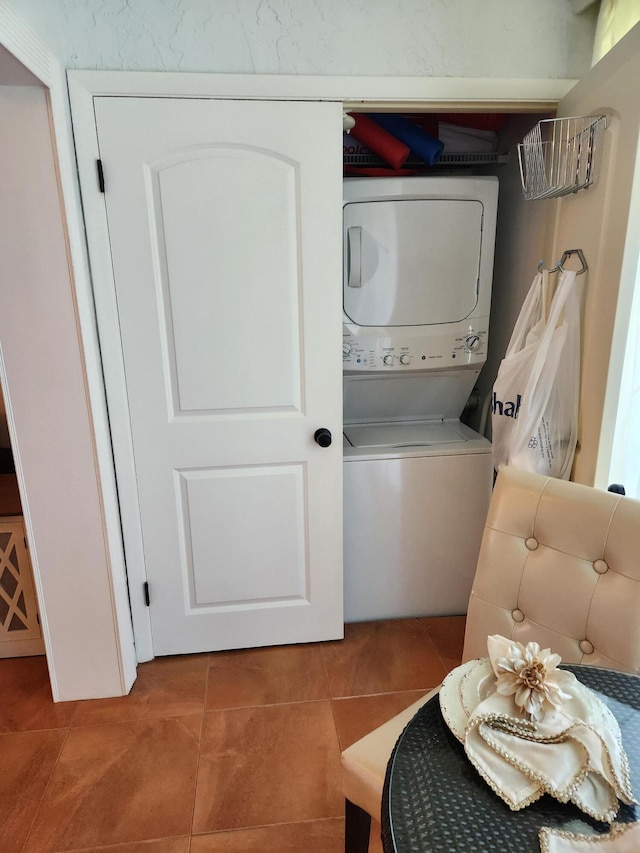 laundry room featuring tile patterned floors and stacked washer / dryer