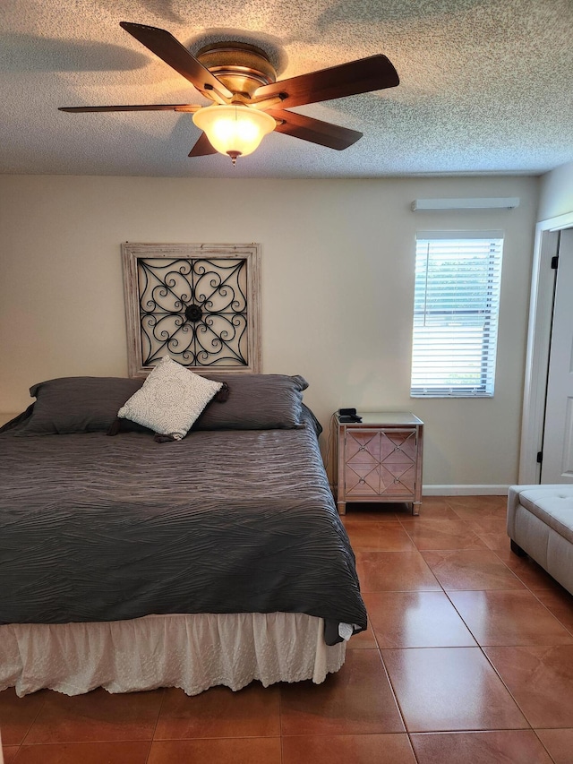 tiled bedroom with ceiling fan and a textured ceiling