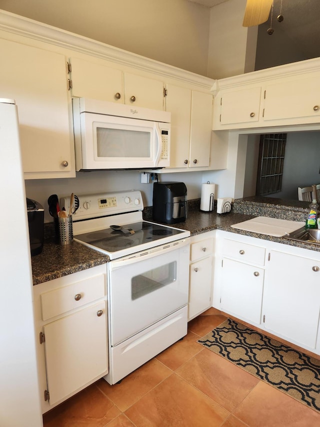 kitchen with white cabinetry, sink, light tile patterned flooring, and white appliances