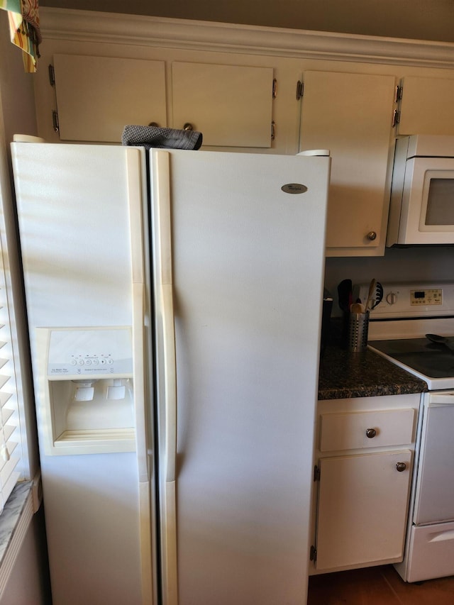 kitchen featuring white cabinets, white appliances, and dark stone counters