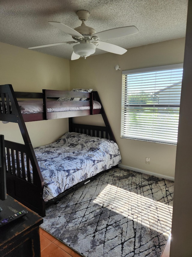 tiled bedroom with ceiling fan and a textured ceiling