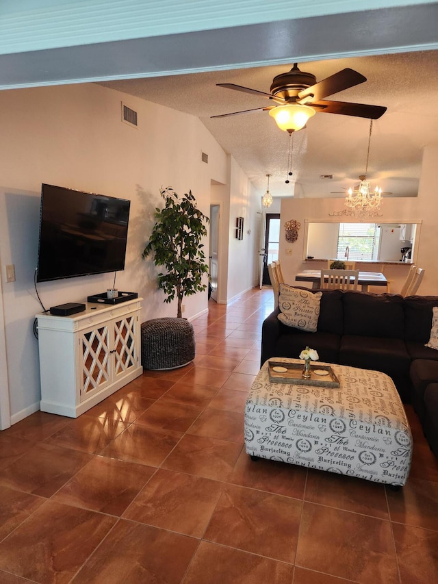 living room featuring ceiling fan with notable chandelier, a textured ceiling, dark tile patterned floors, and lofted ceiling