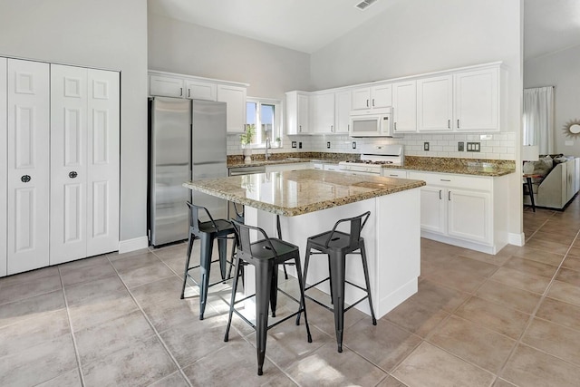 kitchen with white appliances, a kitchen island, white cabinetry, high vaulted ceiling, and light tile patterned floors