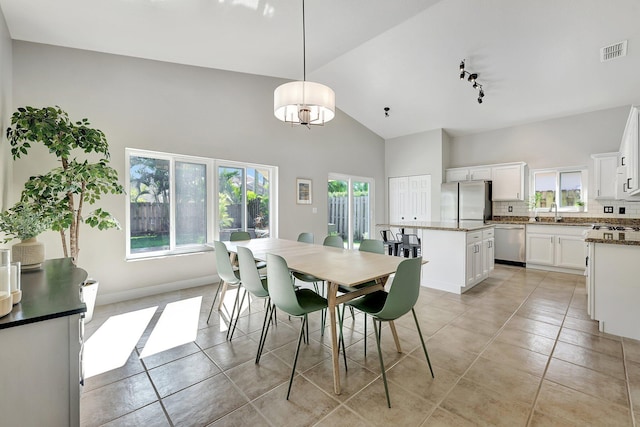 tiled dining space with high vaulted ceiling and sink