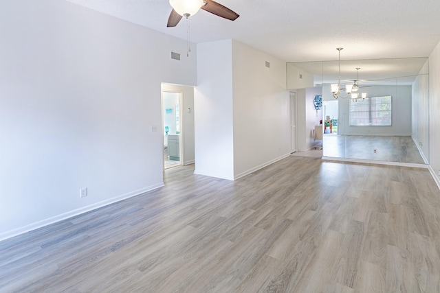 spare room with ceiling fan, a towering ceiling, and light wood-type flooring