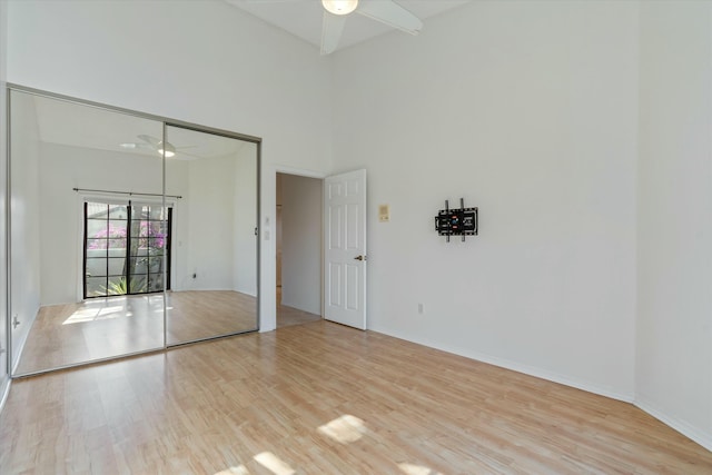 spare room featuring ceiling fan, a high ceiling, and light wood-type flooring