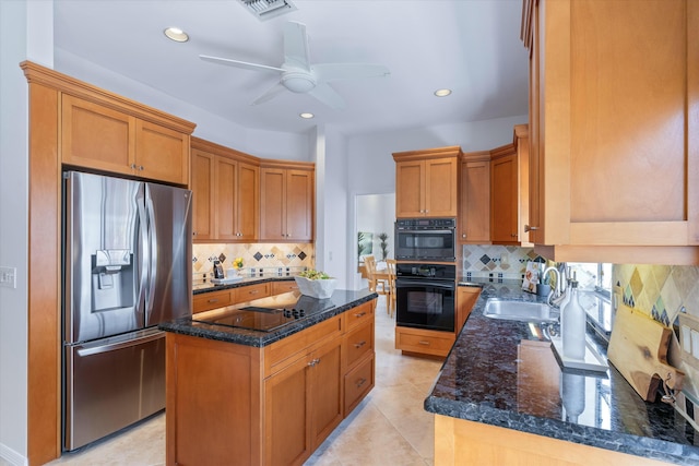 kitchen with black appliances, sink, ceiling fan, dark stone countertops, and a kitchen island