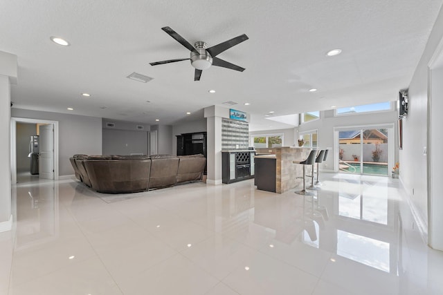 tiled living room featuring a textured ceiling and ceiling fan