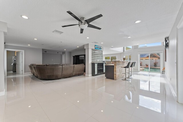 living room featuring a textured ceiling, ceiling fan, and light carpet