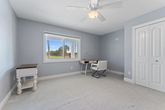 office space with a textured ceiling, ceiling fan, and light carpet