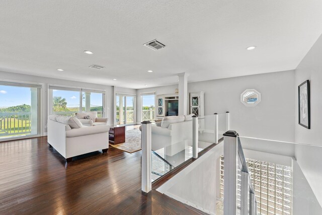 living room featuring a wealth of natural light, decorative columns, and wood-type flooring