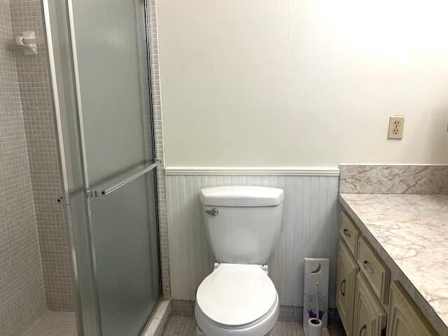 bathroom featuring toilet, an enclosed shower, and vanity