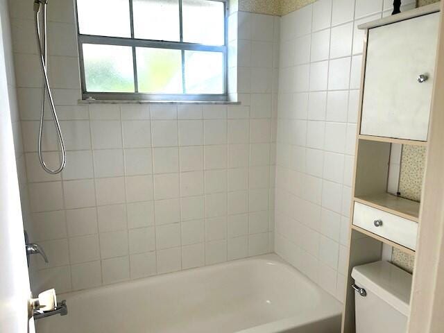 bathroom featuring tiled shower / bath combo and toilet