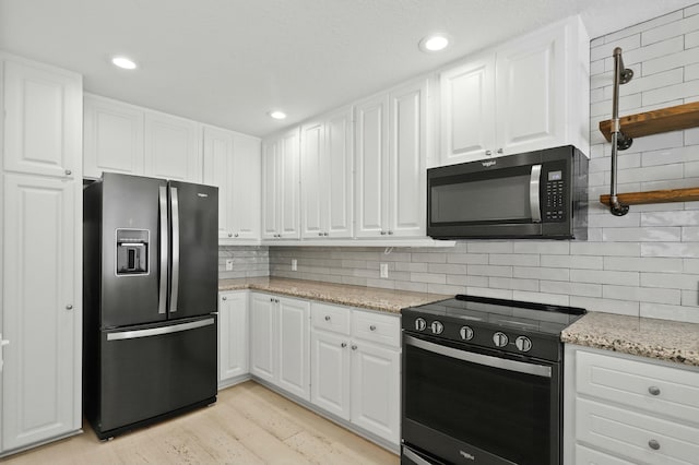 kitchen featuring decorative backsplash, light stone countertops, light hardwood / wood-style floors, white cabinetry, and stainless steel appliances