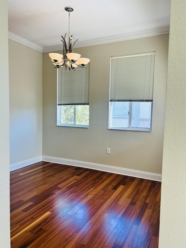 empty room featuring crown molding, dark hardwood / wood-style floors, and an inviting chandelier