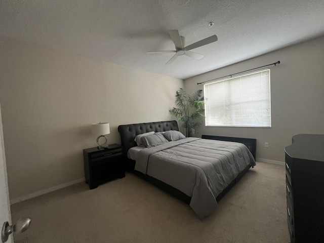 bedroom featuring ceiling fan, light colored carpet, and a textured ceiling