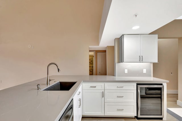 kitchen featuring kitchen peninsula, beverage cooler, sink, dishwasher, and white cabinets