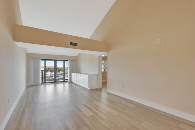 unfurnished living room with a towering ceiling and light wood-type flooring