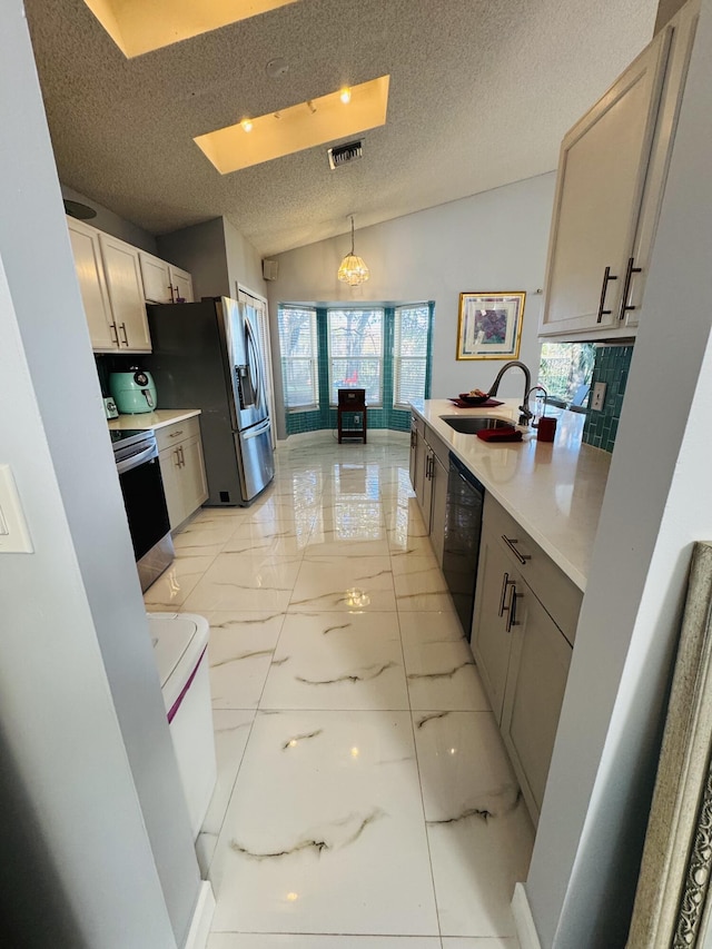 kitchen with lofted ceiling, sink, decorative backsplash, decorative light fixtures, and stainless steel appliances