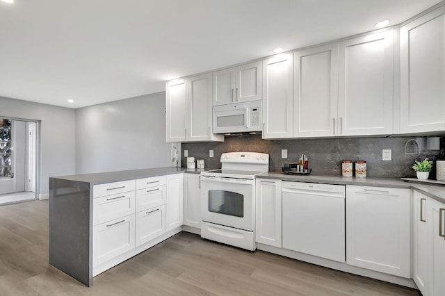 kitchen with kitchen peninsula, white cabinets, and white appliances