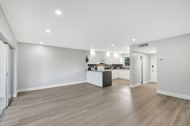 unfurnished living room featuring sink and light hardwood / wood-style floors